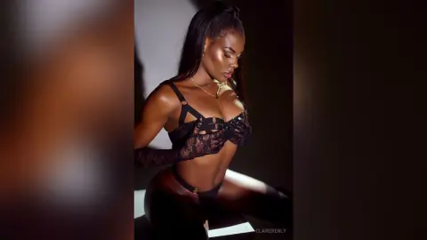 ClaireRenly poses in black lace lingerie and a matching bra, looking down while wearing a gold necklace.
