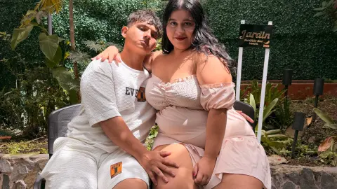 Young couple in casual summer outfits sitting together in a sunny outdoor garden setting.