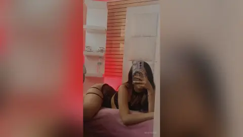 Young woman in black lace lingerie relaxing on a bed in a modern bedroom setting.