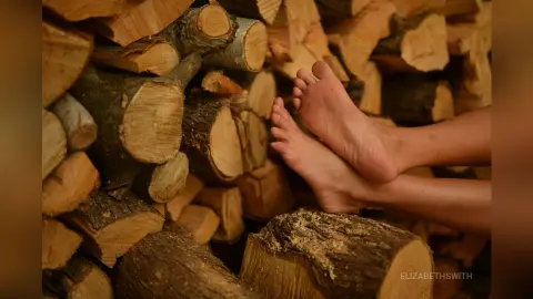 Bare feet resting against a rustic stack of firewood in a cozy, natural outdoor setting.