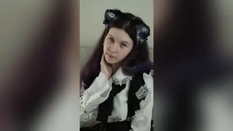 Young woman with purple hair wearing a black and white gothic lace outfit and cat ear headband in a soft mood.