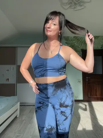 Woman in blue patterned yoga set posing in a sunlit room with a relaxed, casual mood.