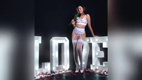 JessieLiu poses in white lace lingerie and white thigh-high stockings, holding a single red rose against a black background.
