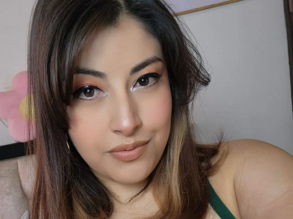 Close-up portrait of a woman with long brown hair and natural makeup in a bright indoor setting.