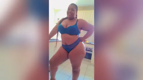 PearlyBrown poses in a blue bra and matching panties, showing off her curves in a kitchen setting.
