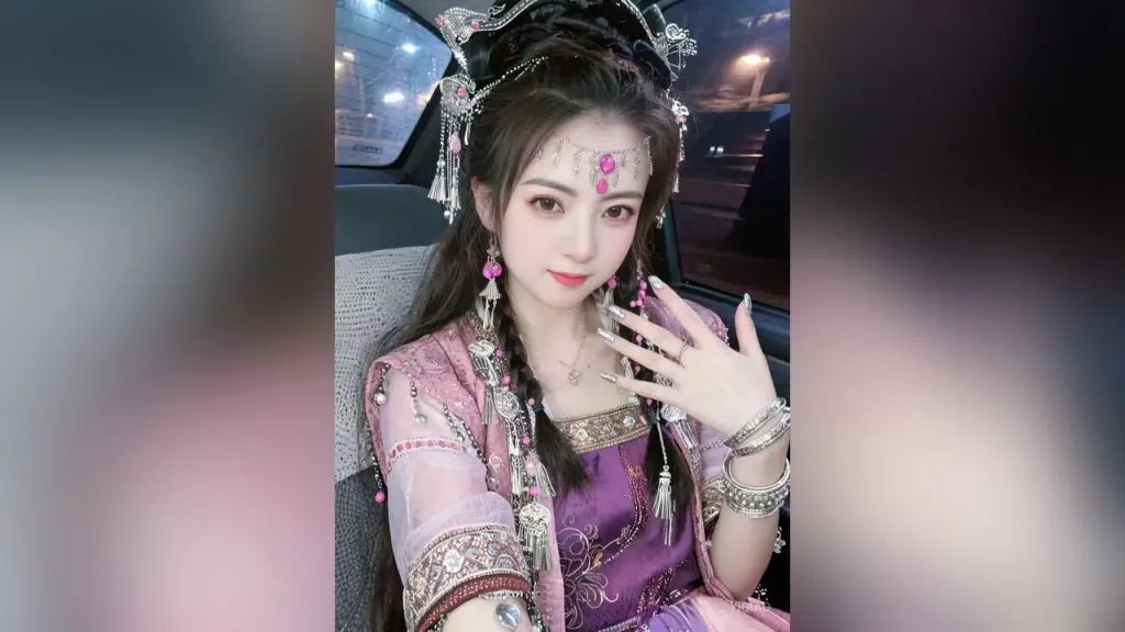 YiQiao — Young woman in ornate pink Hanfu traditional dress and silver headpiece sitting in a car at night.