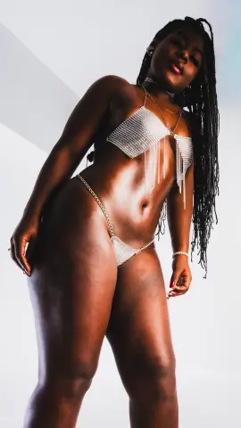 ManelykStorm poses in a silver beaded bikini set with dangling fringe against a white background.