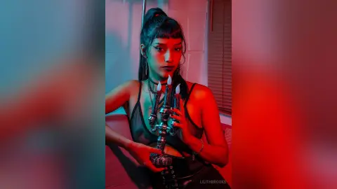 LilithBrooks poses in a black lace bodysuit while holding a lit hookah pipe against a red and blue lit background.