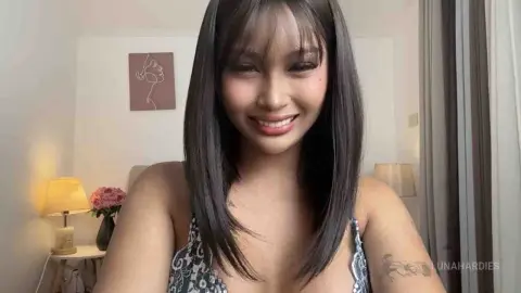 Smiling young woman in a patterned floral top posing in a bright, cozy indoor setting.