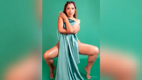 Elegant woman in a teal satin gown posing against a green background with a glamorous mood.