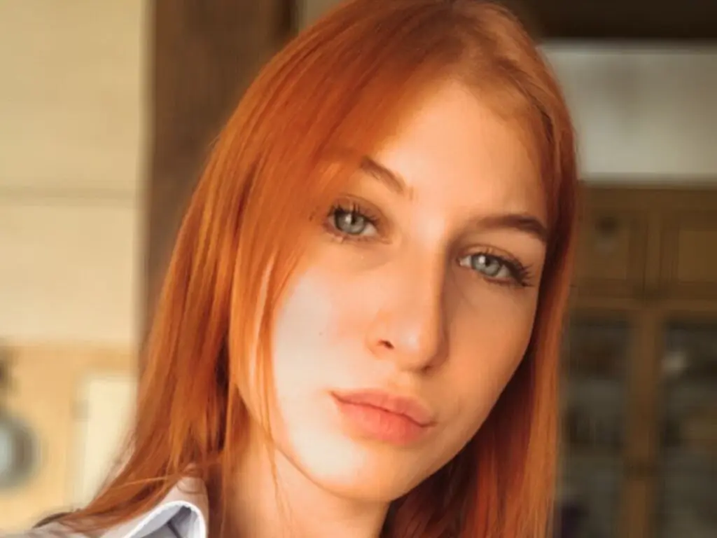 Portrait of a redheaded woman in a white shirt with a soft, natural indoor lighting mood.