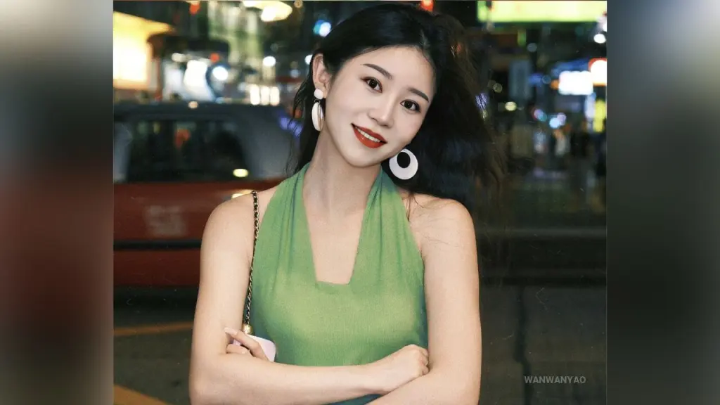 WanwanYao — Smiling young woman in a green halter top posing outdoors at night in a city setting.