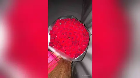 Large bouquet of vibrant red roses wrapped in paper for a romantic Valentine's Day gift.