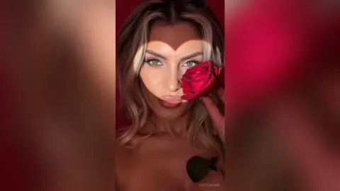 JessycaPage poses with a red rose held near her face, framed by a heart-shaped light effect over her eyes.