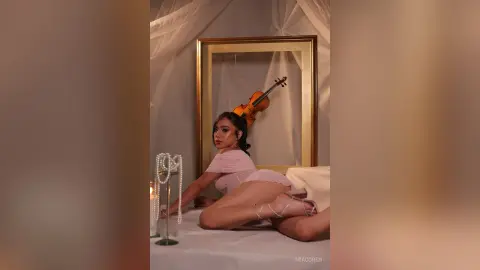Elegant woman in a pink silk outfit lounging in a dreamy, romantic bedroom setting with a vintage violin.