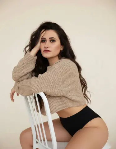 Mia_Crush poses sitting on a white chair wearing a tan ribbed sweater and black panties.