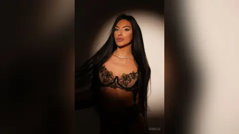 Iza — Elegant woman in black lace lingerie and silver necklace posing in dramatic studio lighting.