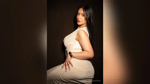 Elegant woman in a white sleeveless dress posing against a dark background with a sophisticated mood.