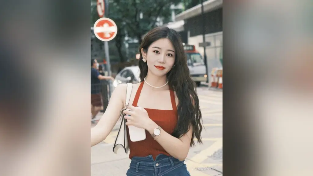 WanwanYao — Smiling young woman in a red tank top and jeans posing on a city street during the day.
