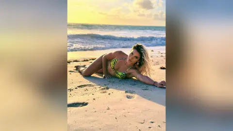 JessycaPage lies on the beach in a yellow bikini top as the sun sets over the ocean waves.