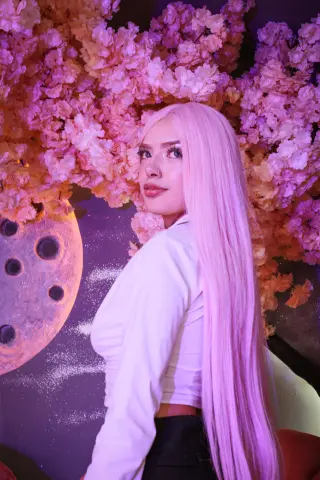 BabyVelvett poses with her long pink hair against a background of pink flowers.