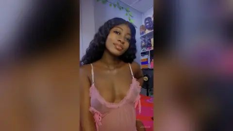 JoanJon poses in a pink lace chemise with her long dark wavy hair flowing over her shoulders.