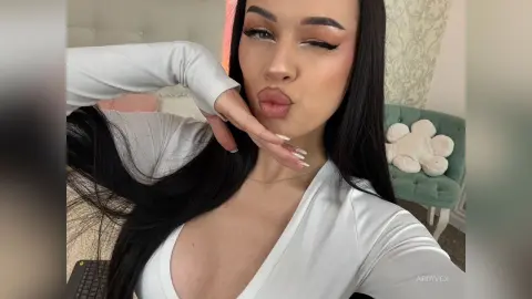 AriaVex pouts her lips while wearing a white long-sleeved top with a deep v-neckline.