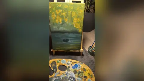 Impressionist oil painting of a lonely boat on a dark lake under golden trees on a wooden artist easel.