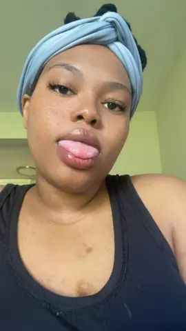 MilfArie22 wearing a light blue headband and black tank top, sticking her tongue out at the camera.