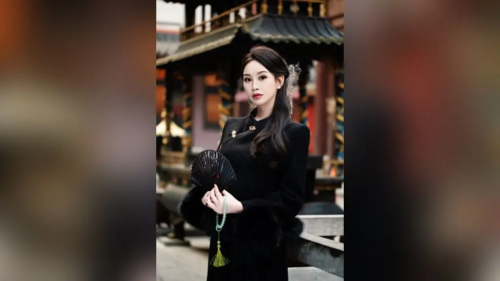 XiaoJuan — XiaoJuan poses in a black traditional dress, holding a black folding fan against a temple background.