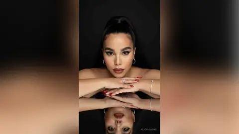 Glamorous woman with high ponytail and elegant makeup posing against a dark background.