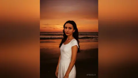 Young woman in a white summer dress standing on a beach during a warm golden sunset.