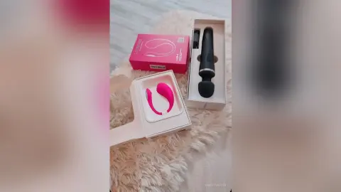 Pink and black wellness devices in white packaging resting on a soft white faux fur surface.