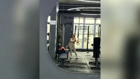 AlmaKane — Athletic woman in white sports bra and leggings training in a modern, bright home gym setting.