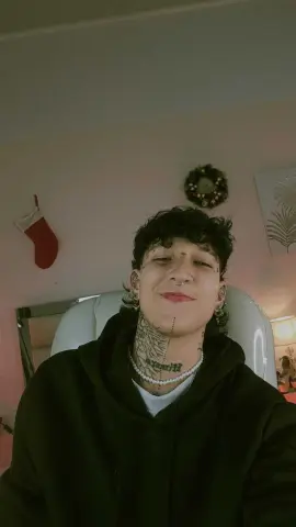 lucirosee smiles with her eyes closed, showing her short dark curly hair, nose ring, and neck tattoos while wearing a black hoodie and pearl necklace.