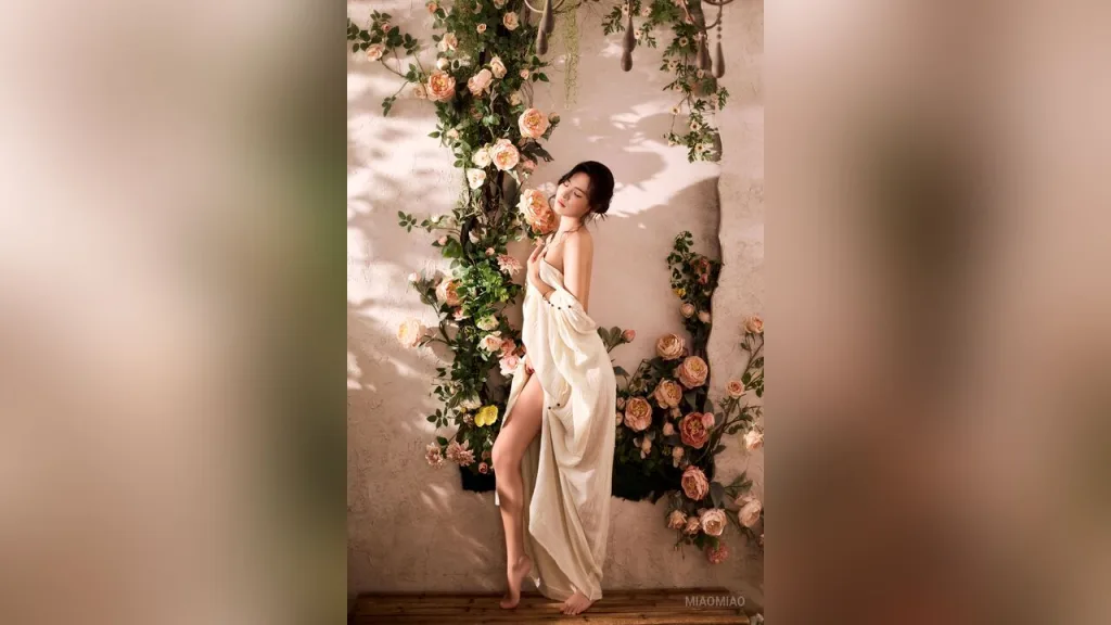 miaomiao — miaomiao poses wrapped in a white sheet amidst peach roses against a textured wall.