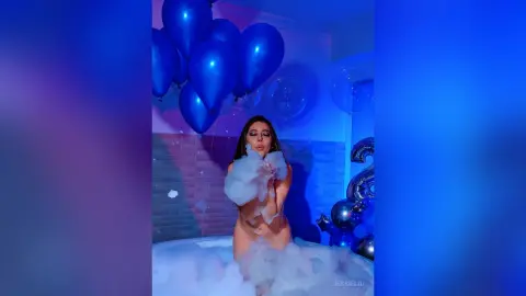 JessieLiu poses naked in a white bubble bath, holding thick white foam against her breasts and chest.