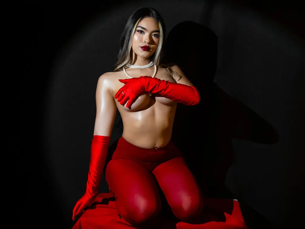 Glamorous woman in red gloves and tights posing against a dark background with dramatic lighting.