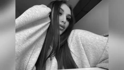 Young woman with long hair wearing a cozy oversized sweatshirt in a moody black and white portrait.