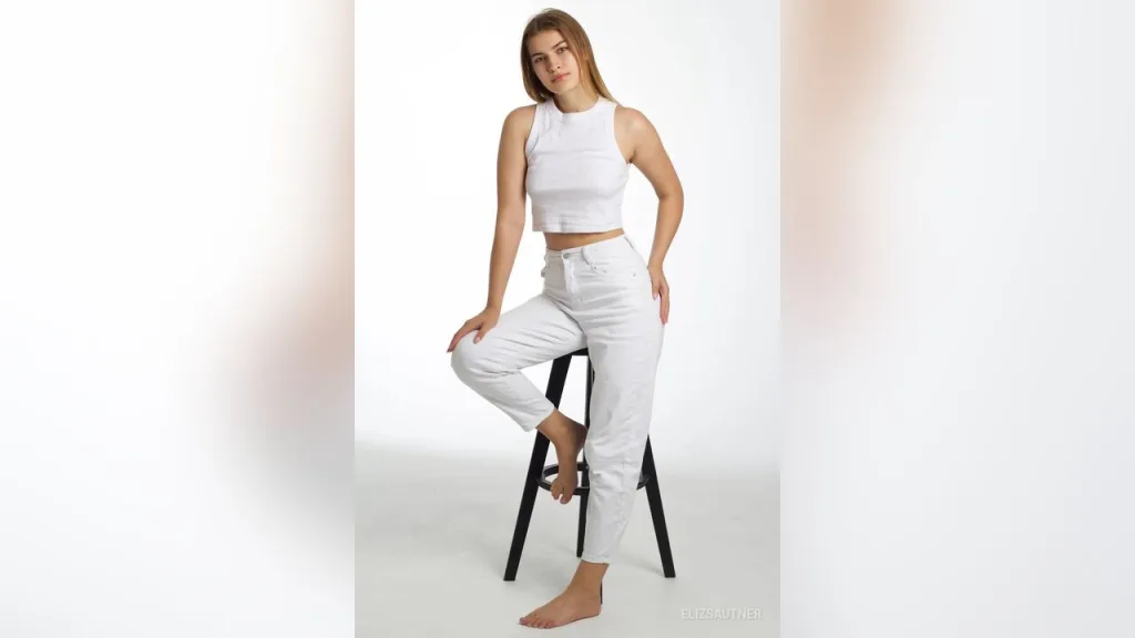 ElizSautner rests her chin on her hand, looking forward with long blonde hair against a white background.