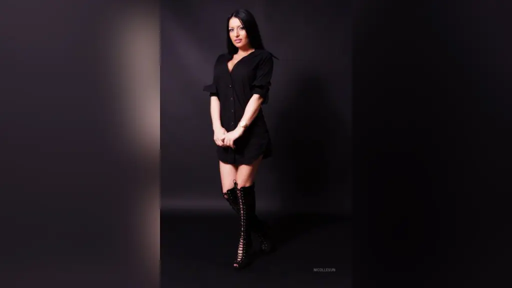 Portrait of a brunette woman in a black bra and open shirt against a dark studio background.