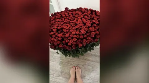 AlienaMoore — AlienaMoore sits on a light wood floor behind a massive bouquet of red roses.