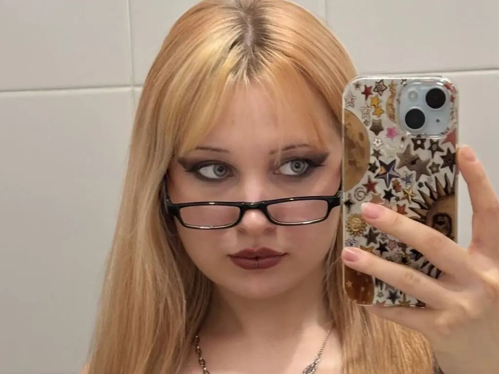 EloiseGow takes a mirror selfie wearing black glasses and showing off her long blonde hair.