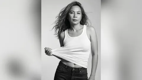 MilaSwan — MilaSwan lifts her white tank top while posing in denim jeans against a plain background.