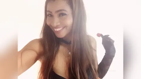 KiaraParker smiles while wearing a black choker and black lace gloves against a white background.