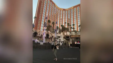Woman in casual black top and green pants standing in front of the Treasure Island hotel in Las Vegas.