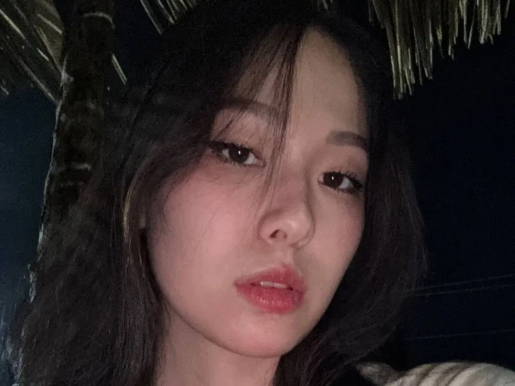 Close-up portrait of a young woman with long dark hair in a moody, nighttime outdoor setting.