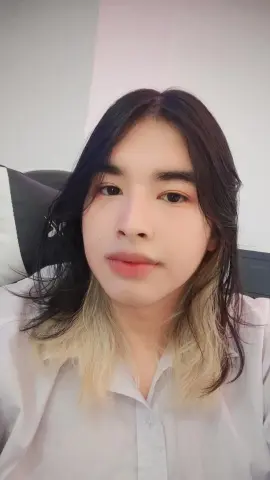 Young woman with long dark hair and white shirt posing in a bright indoor setting with a calm expression.