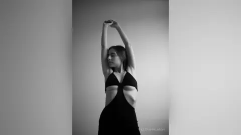 Elegant woman in a black cutout dress posing gracefully in a minimalist studio setting, black and white photography.