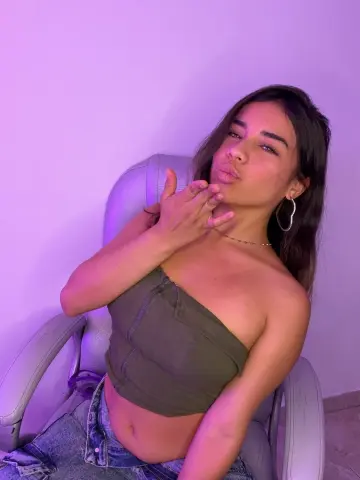 zuerosse18 pouts her lips while sitting in a chair wearing an olive tube top and denim shorts.